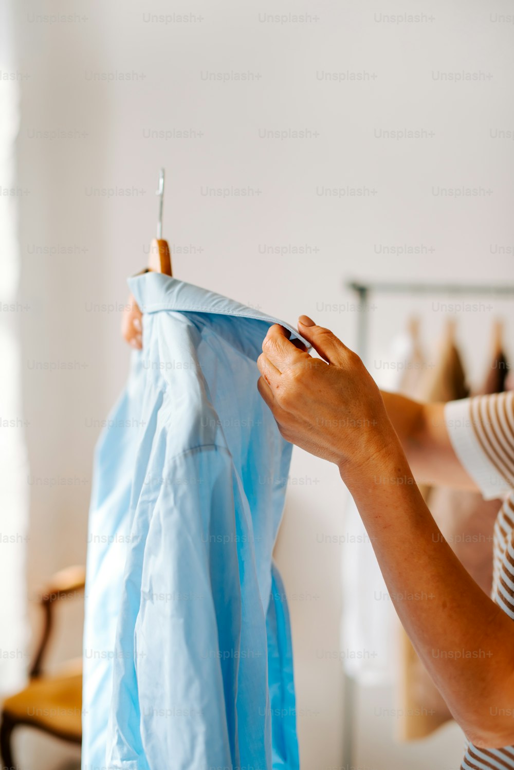 a woman holding a blue shirt on a clothes line