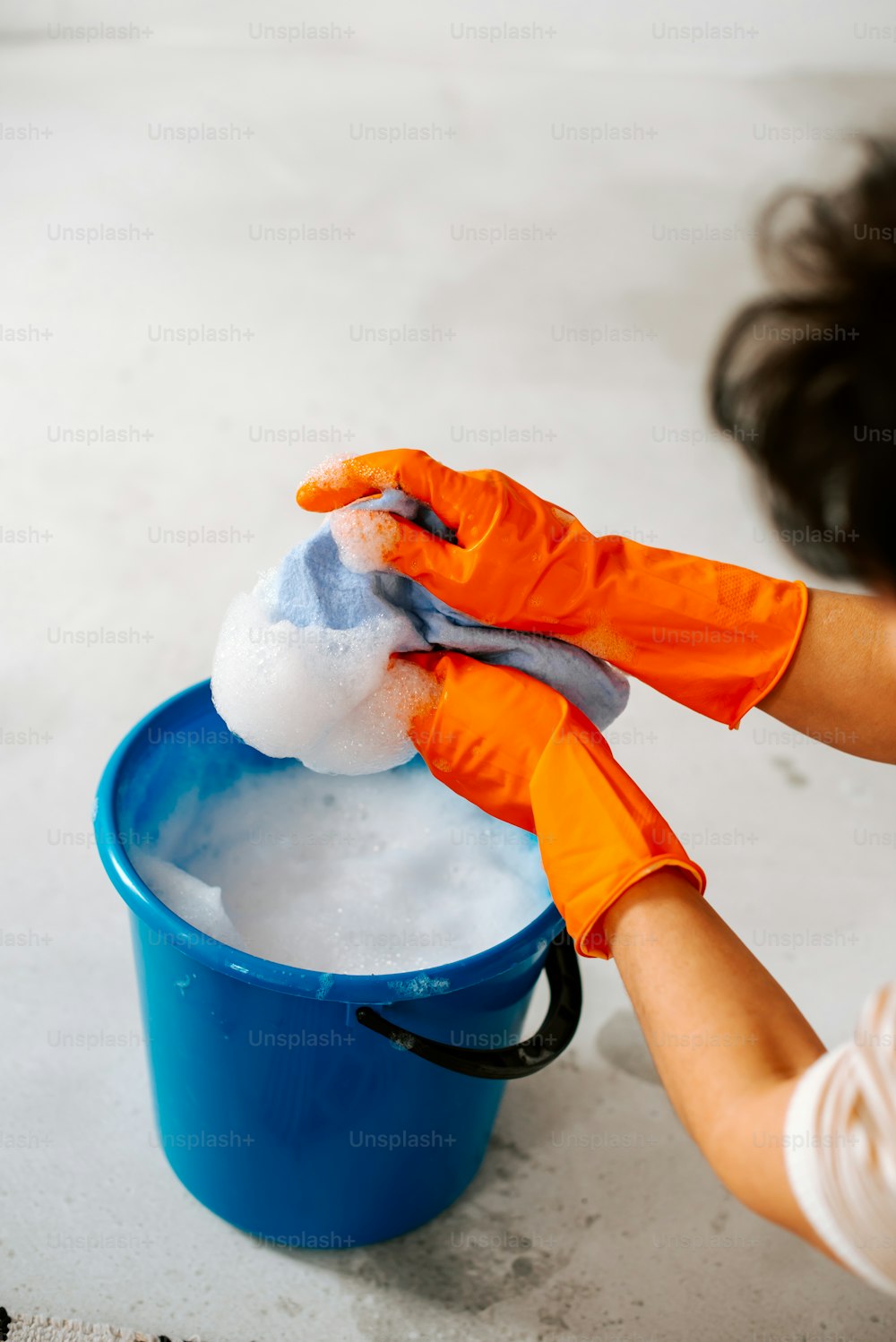 a woman is cleaning a bucket with a rag