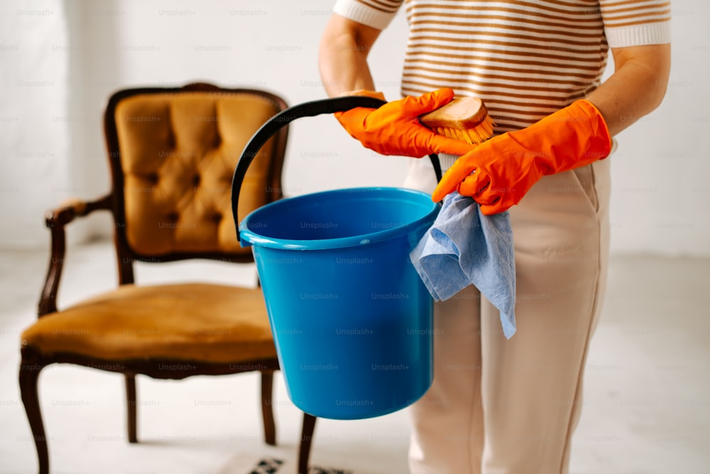 a person in a striped shirt is holding a blue bucket