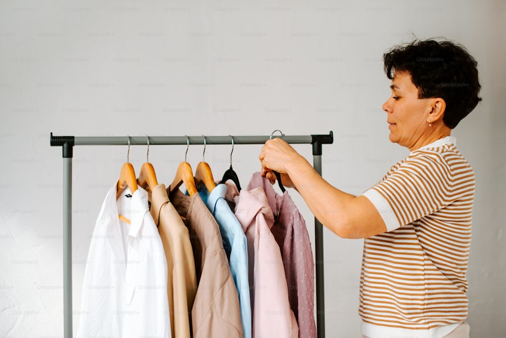 a woman looking at a rack of shirts