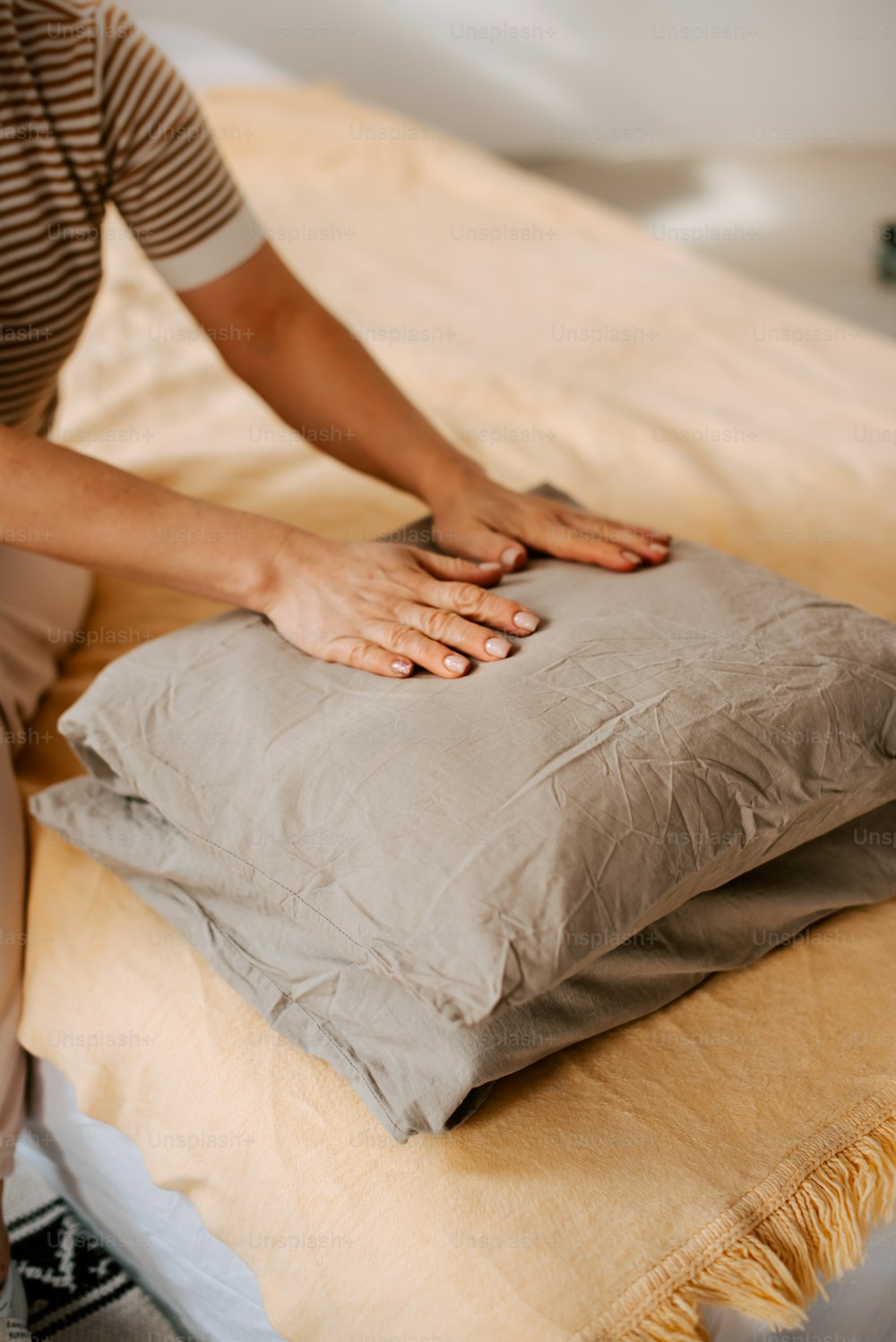 a woman is placing a pillow on a bed