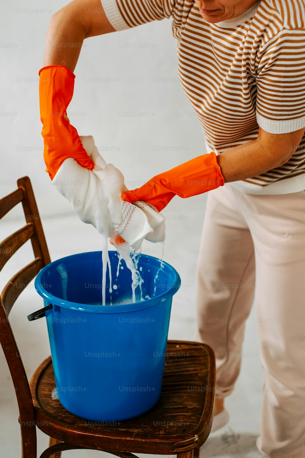 a woman in striped shirt pouring water into a blue bucket