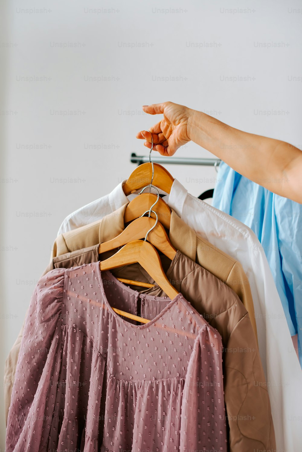 a woman's hand reaching for a shirt on a hanger