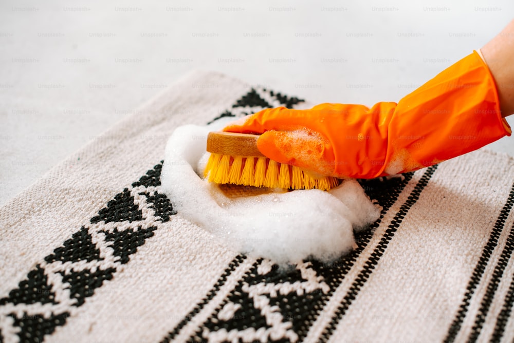 a person cleaning a rug with a yellow brush