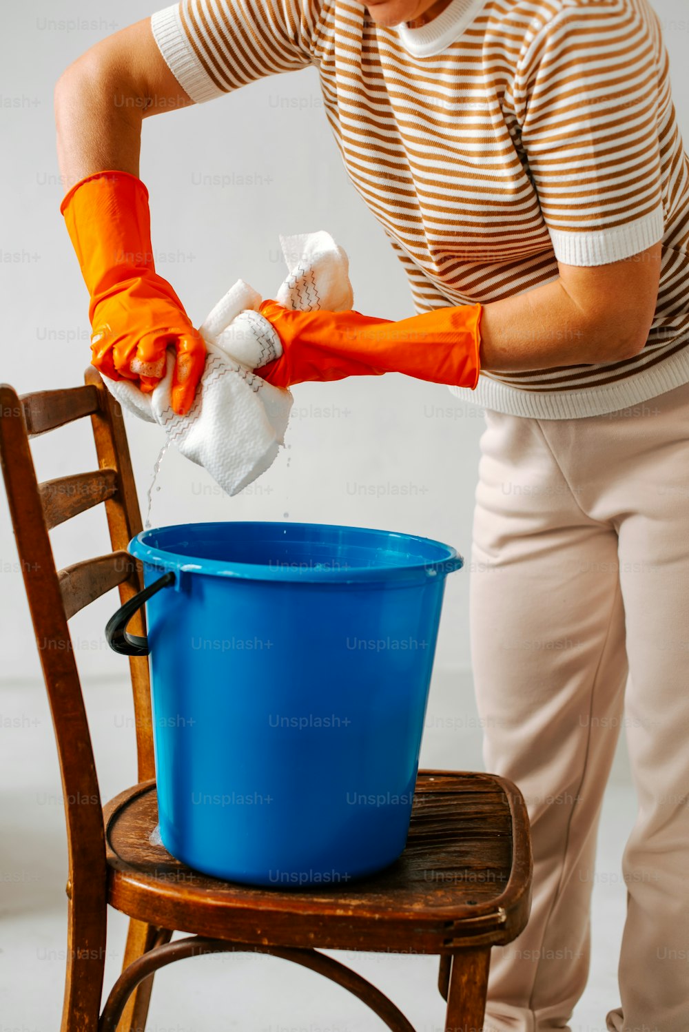 a woman in a striped shirt is cleaning a blue bucket