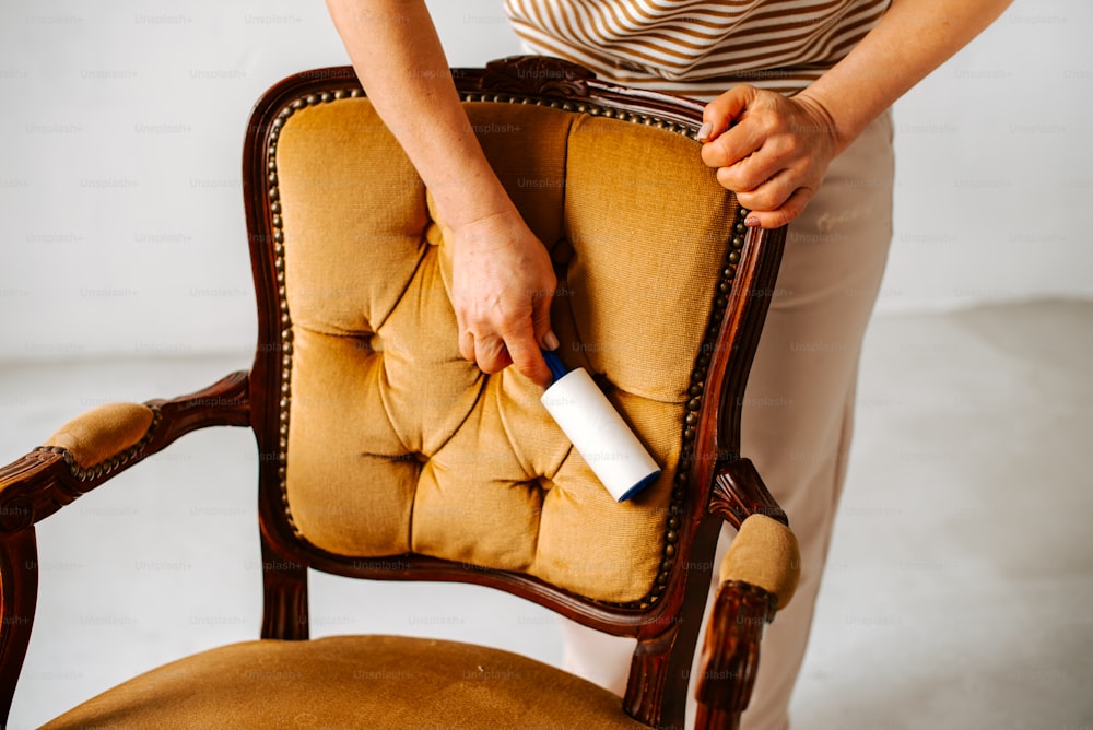 Una mujer sostiene un rodillo de pintura en una silla