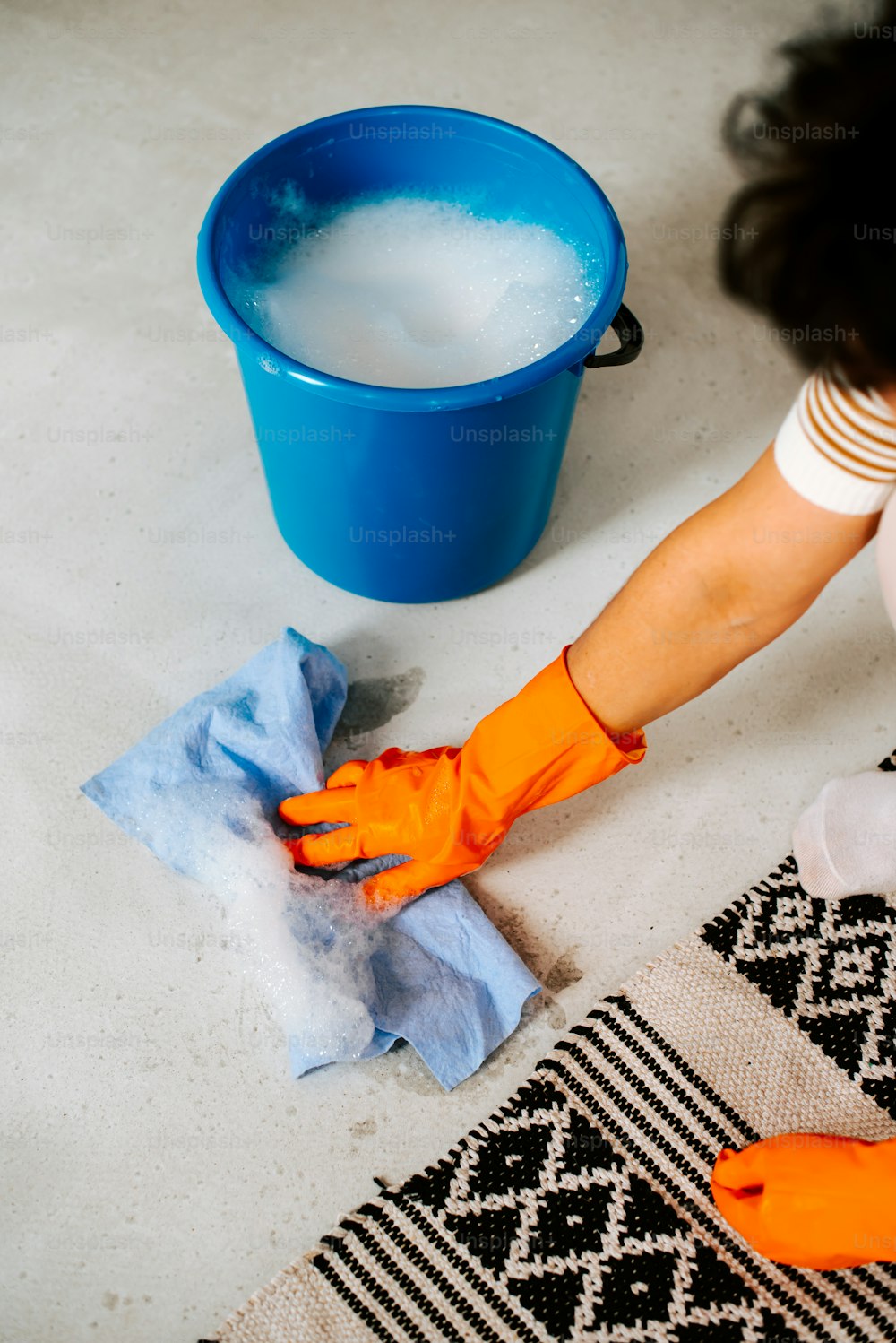 a woman is cleaning the floor with a blue bucket