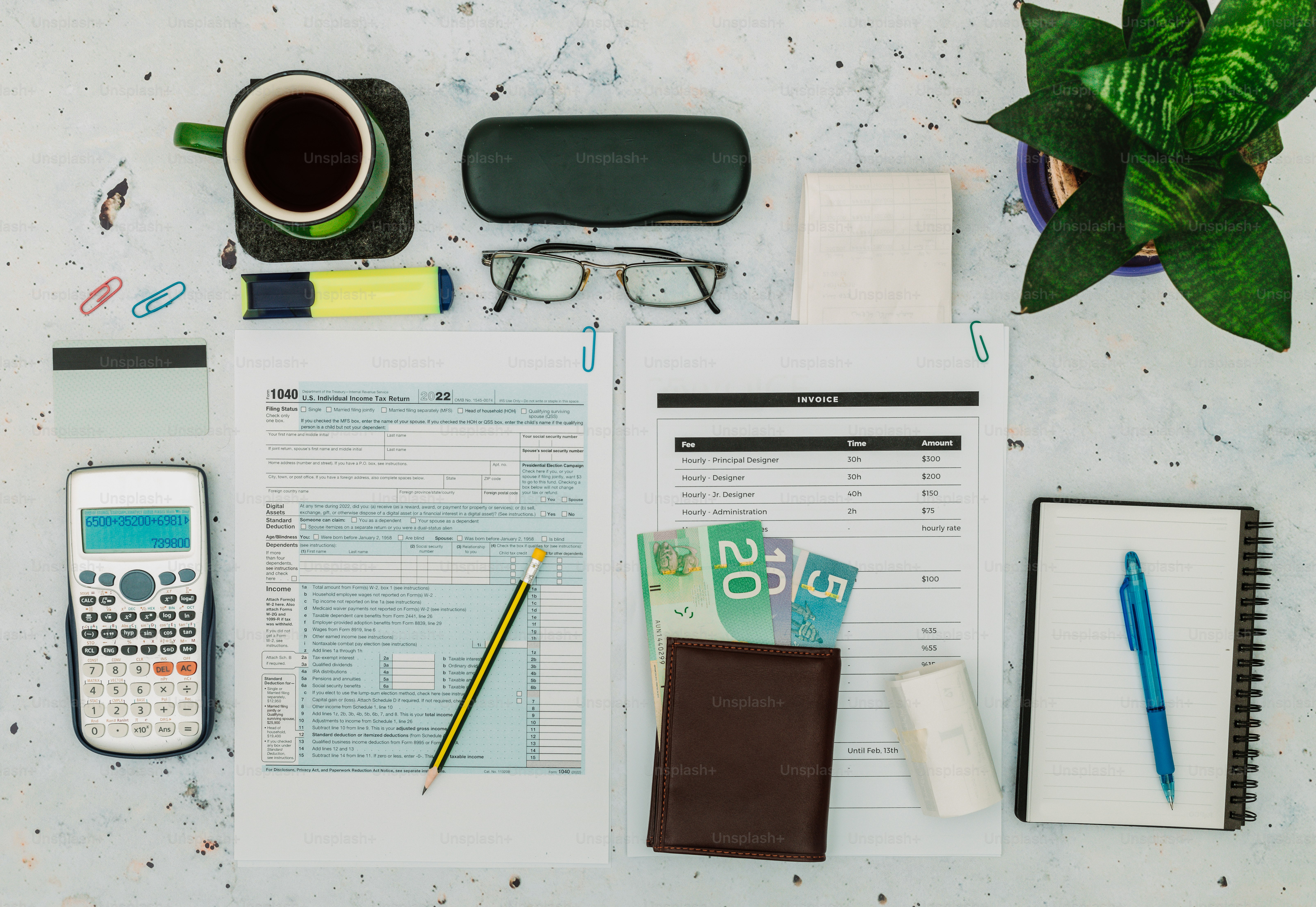 a desk with a notebook, calculator, pen and glasses