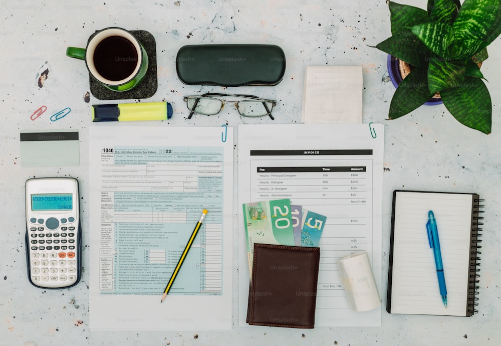 a desk with a notebook, calculator, pen and glasses