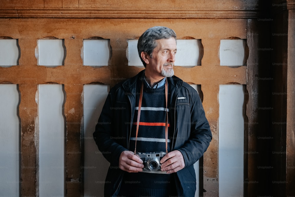 a man standing in front of a wooden wall holding a camera