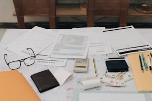 a table topped with lots of papers and a calculator