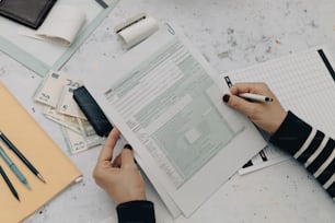 a person holding a pen and writing on a piece of paper