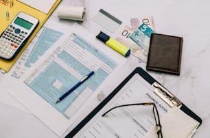 a desk with a calculator, pen, glasses and papers