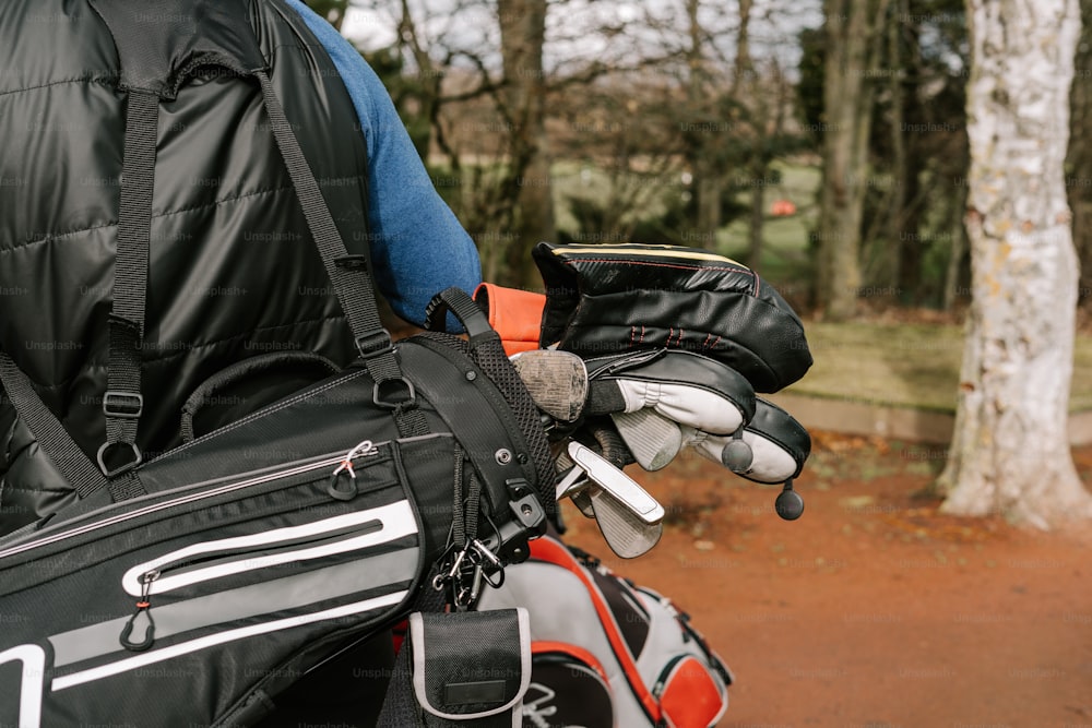 Una persona sosteniendo una bolsa de golf y guantes de golf