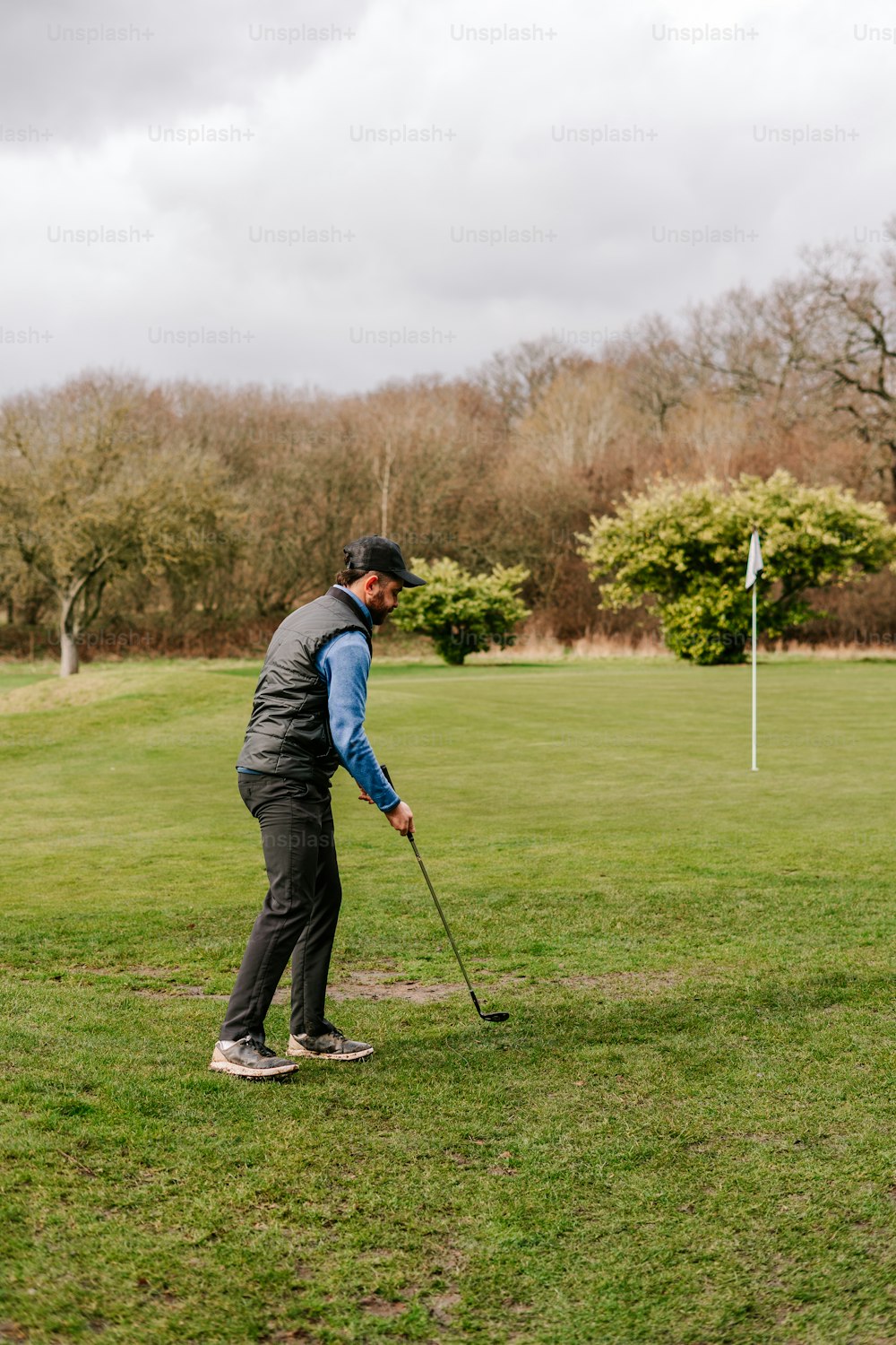 Un uomo che tiene una mazza da golf in cima a un campo verde lussureggiante