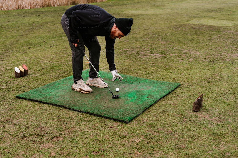 a man putting a golf ball on a green mat