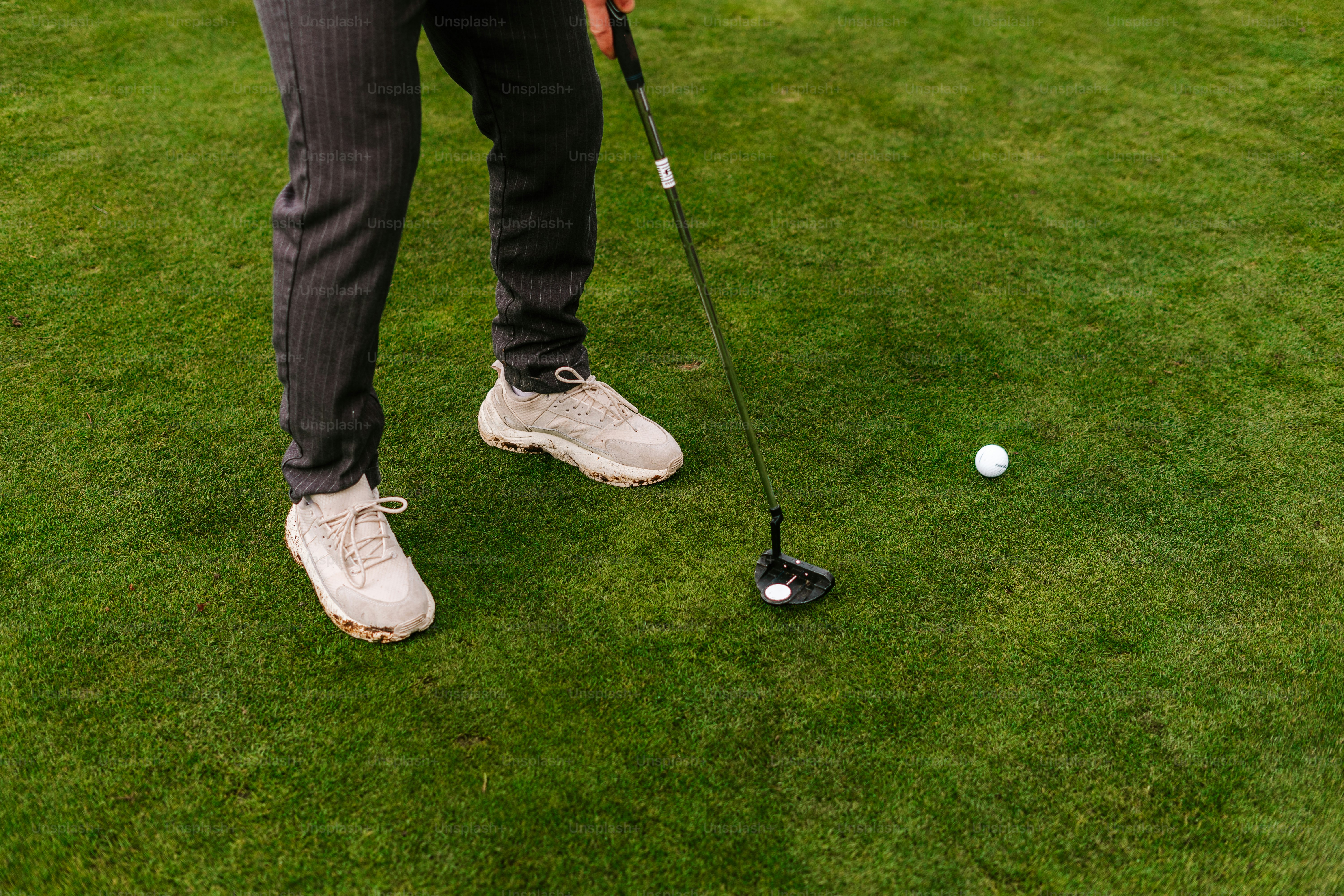 A man standing on top of a lush green field next to a golf ball photo ...