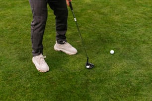 a man standing on top of a lush green field next to a golf ball