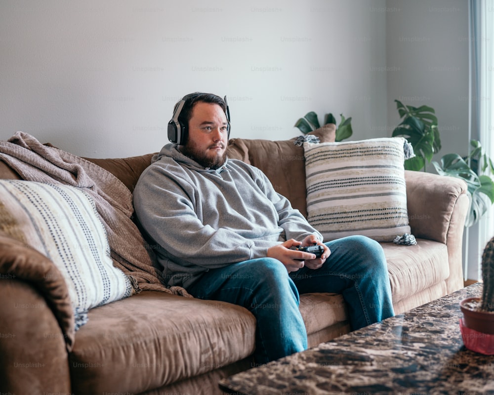 ソファに座ってビデオゲームをしている男性