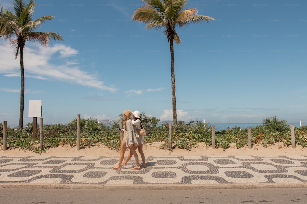 two people walking down a sidewalk with palm trees in the background