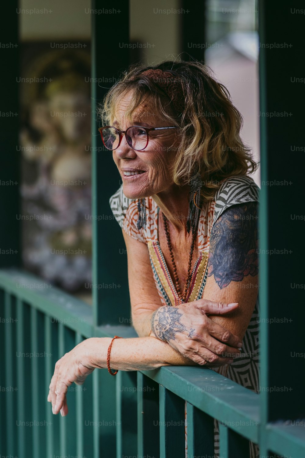 Una donna con tatuaggi sul braccio appoggiata a una ringhiera