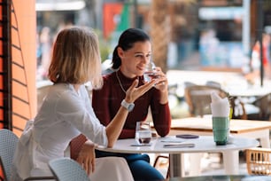 two women sitting at a table drinking wine