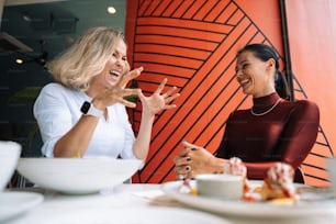 a couple of women sitting at a table with plates of food