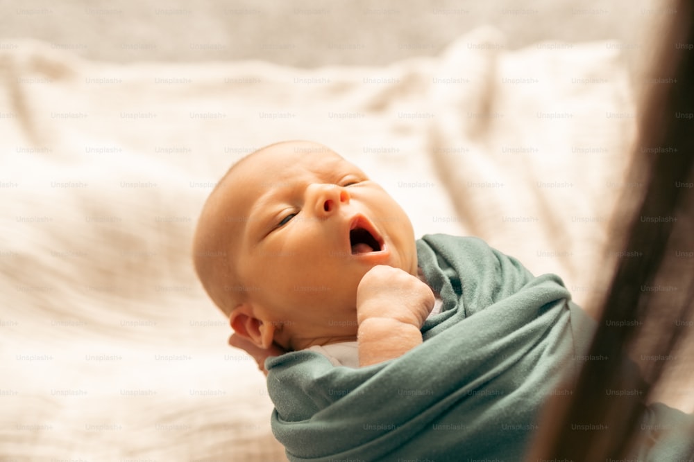a baby is laying on a bed and yawning