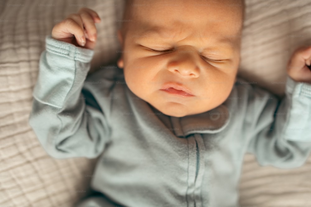 Ein Baby, das mit den Händen auf dem Kopf auf einem Bett liegt