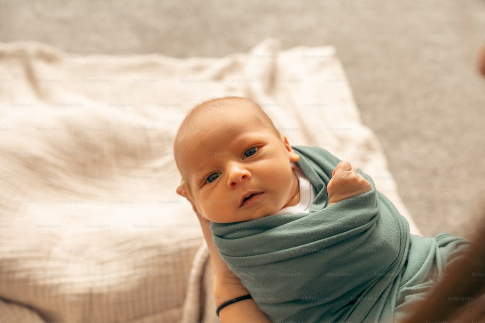 um bebê enrolado em um cobertor sentado em uma cama