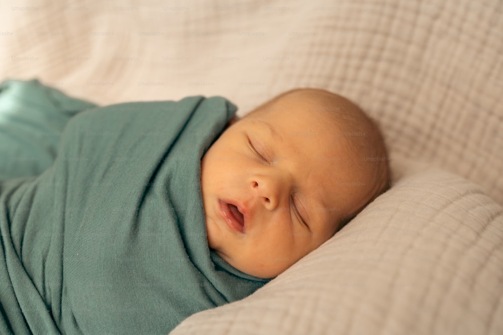 a baby wrapped in a blanket sleeping on a bed