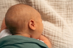 Un bebé acostado encima de una cama junto a una manta