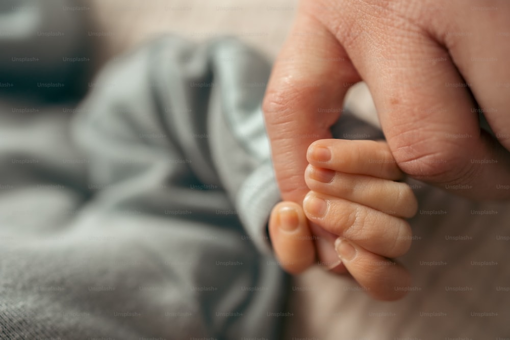 a person holding a baby's hand on top of a bed