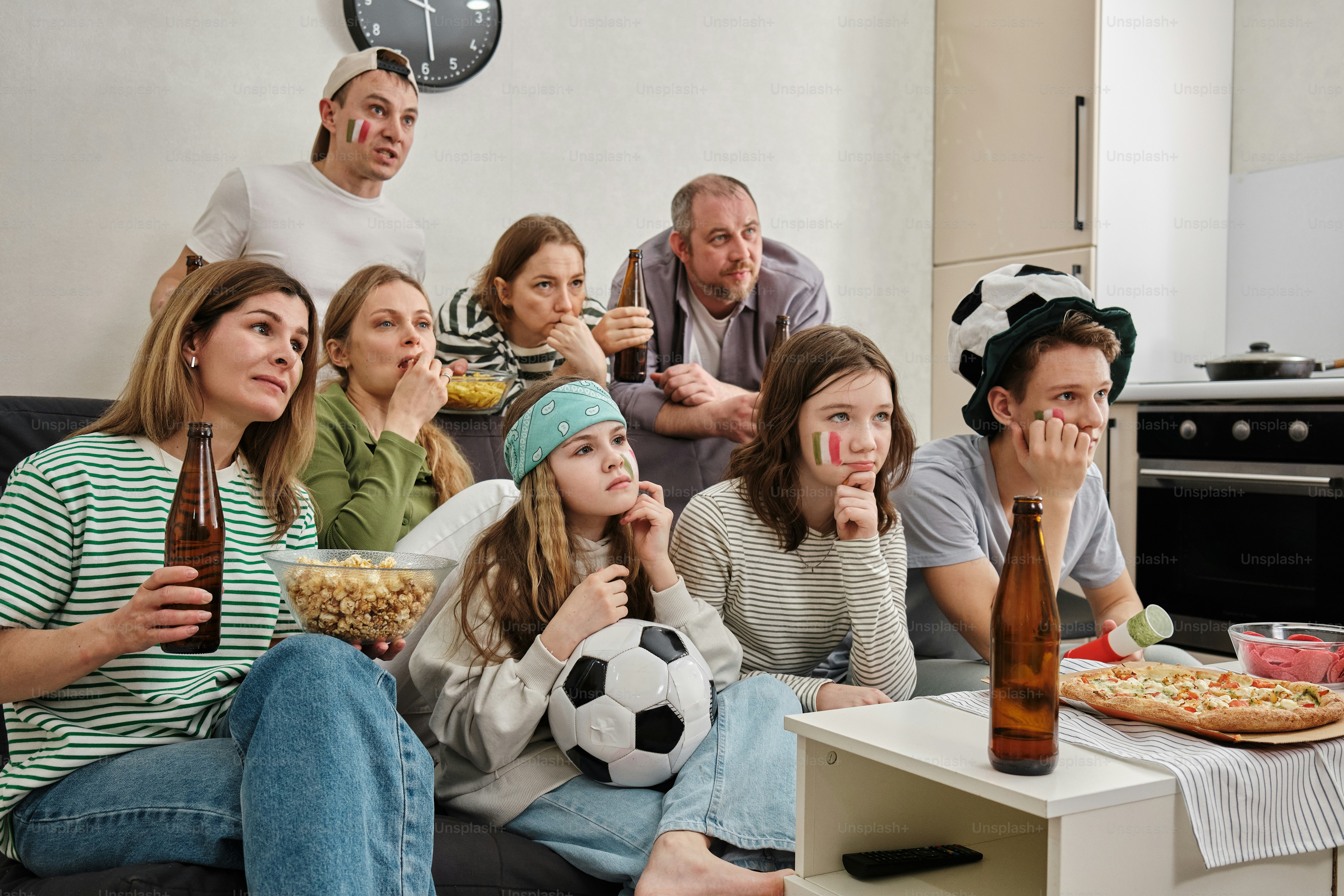 A group of people sitting on a couch in a living room photo – Sport ...
