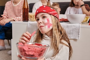 a little girl with a red cross painted on her face