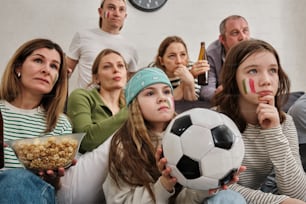 Un gruppo di persone sedute su un divano con un pallone da calcio