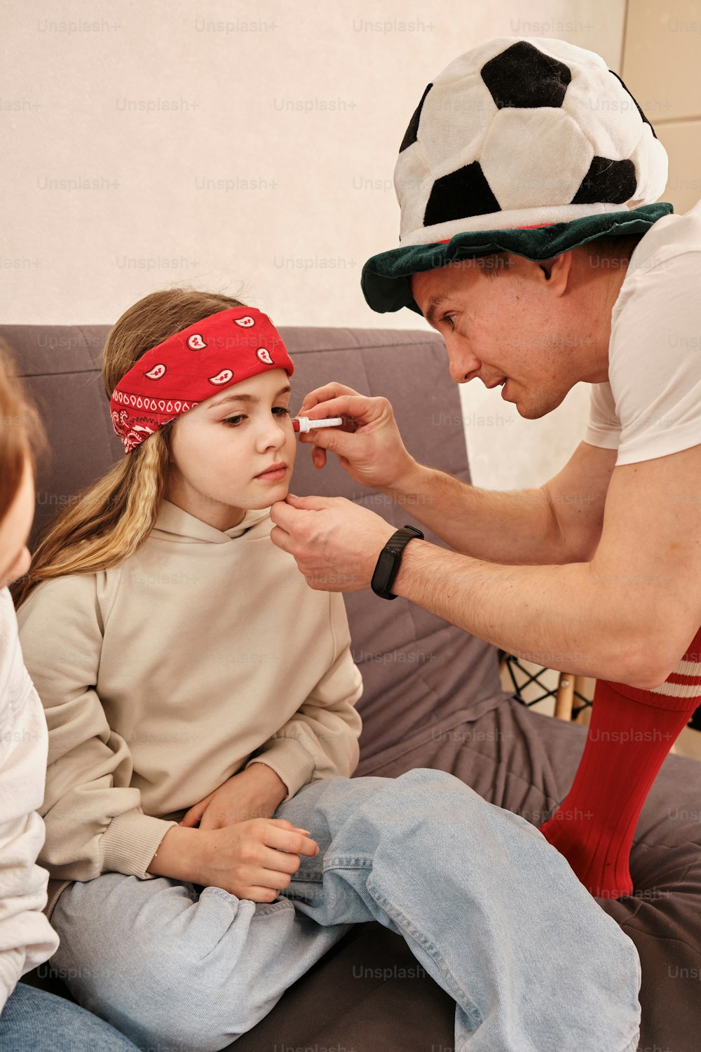 a man is putting something on a little girl's face