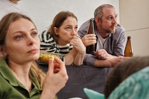 a group of people sitting on a couch drinking beer