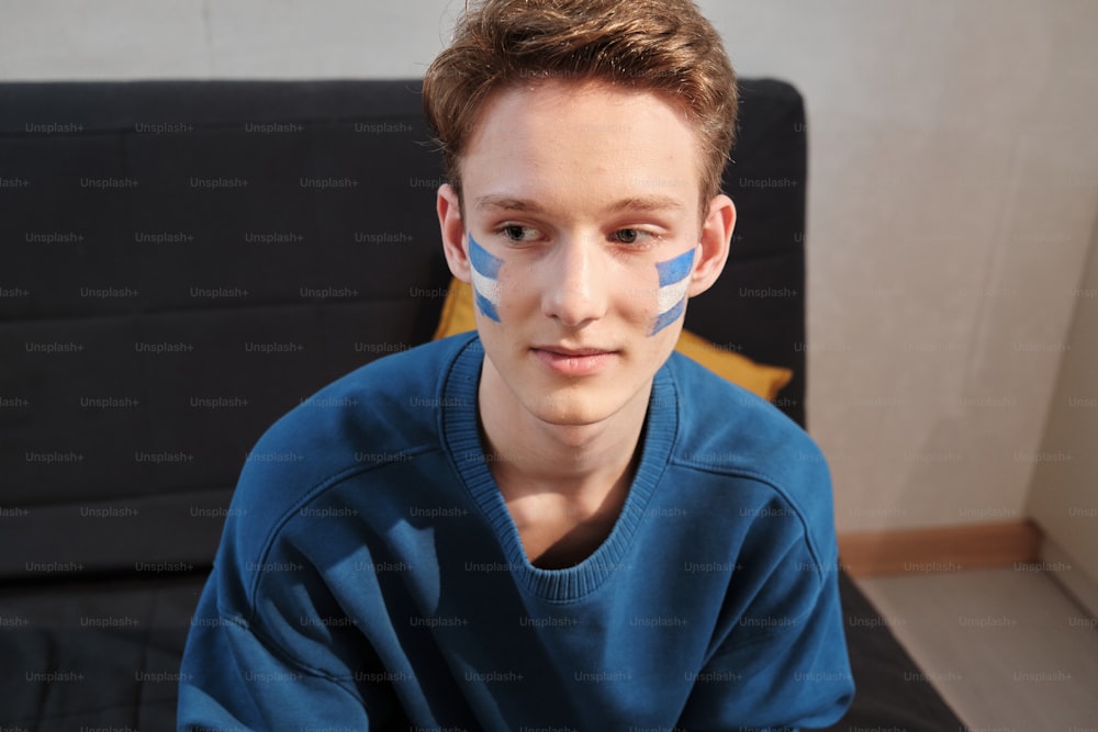 a boy with a painted face sitting on a couch