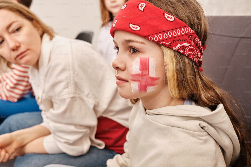 una bambina con una croce rossa dipinta sul viso