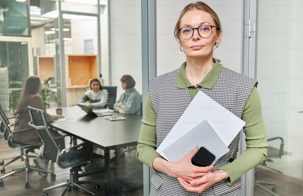 Una mujer parada en una oficina sosteniendo un pedazo de papel