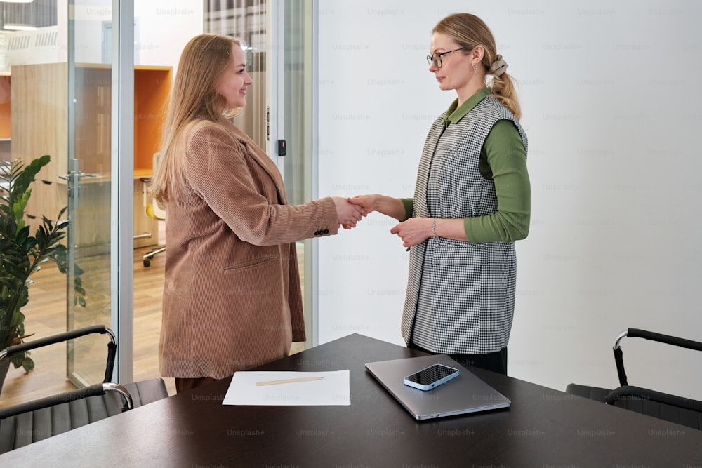 duas mulheres apertando as mãos em um ambiente de escritório