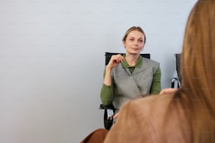 Eine Frau, die auf einem Stuhl sitzt und ihr Spiegelbild betrachtet