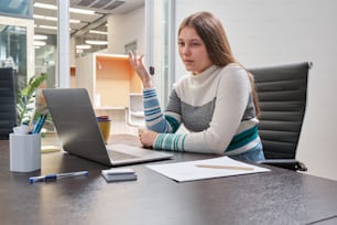 a woman sitting at a desk using a laptop computer