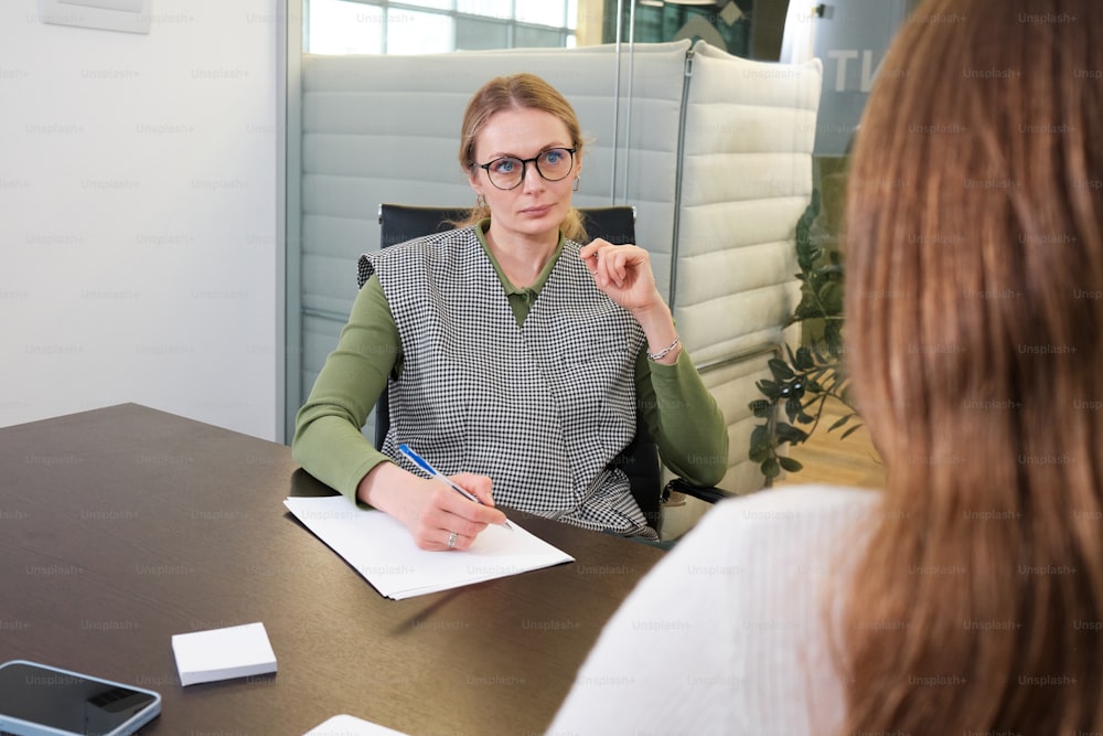 a woman sitting at a desk with a notepad and pen