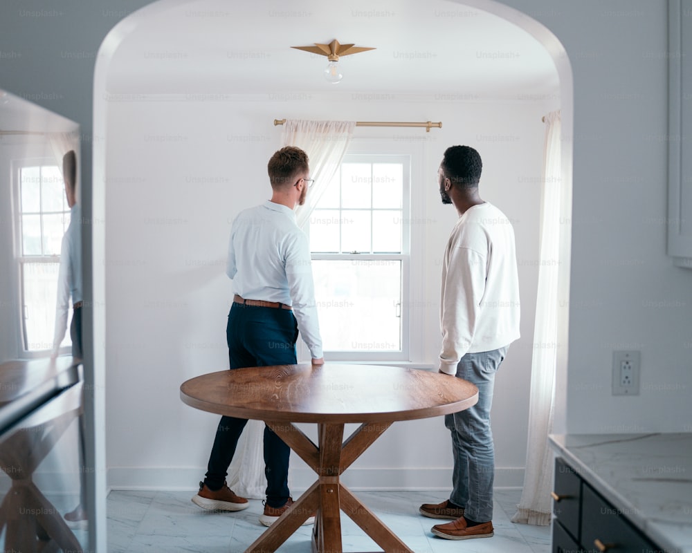 a couple of men standing next to a wooden table