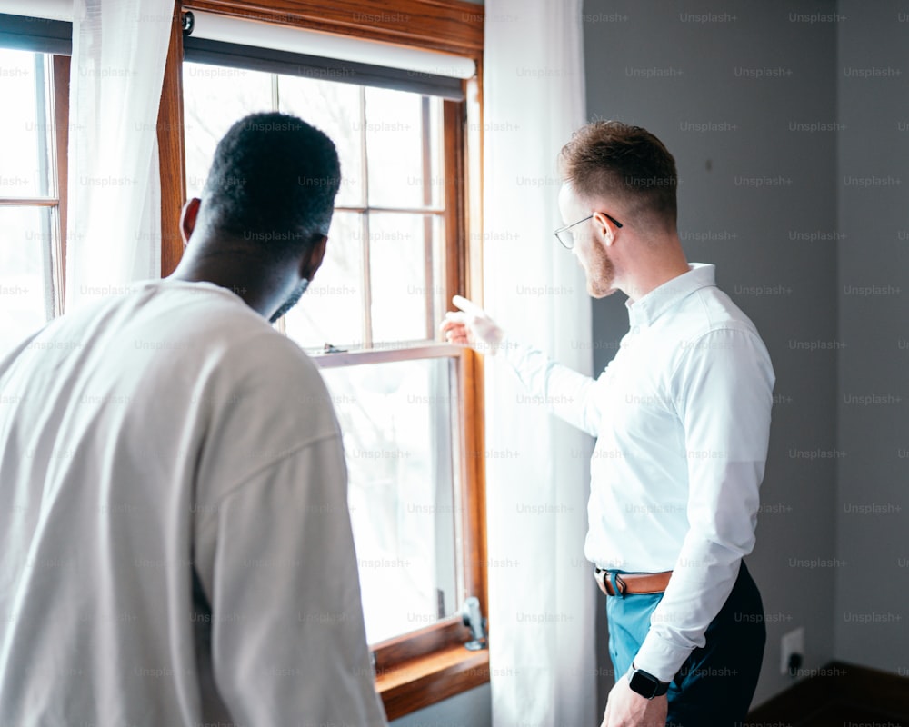 a man in a white shirt is looking out a window