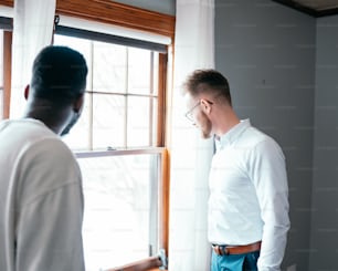 a man standing in front of a window next to another man