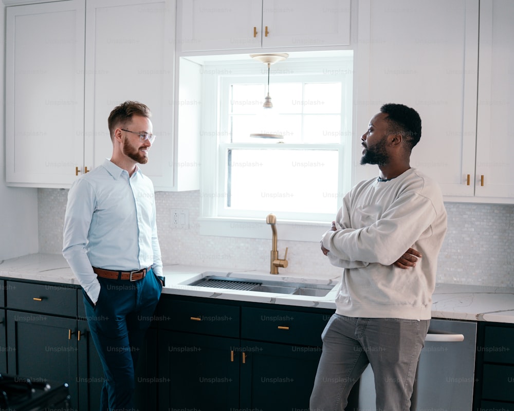 a couple of men standing in a kitchen next to a sink