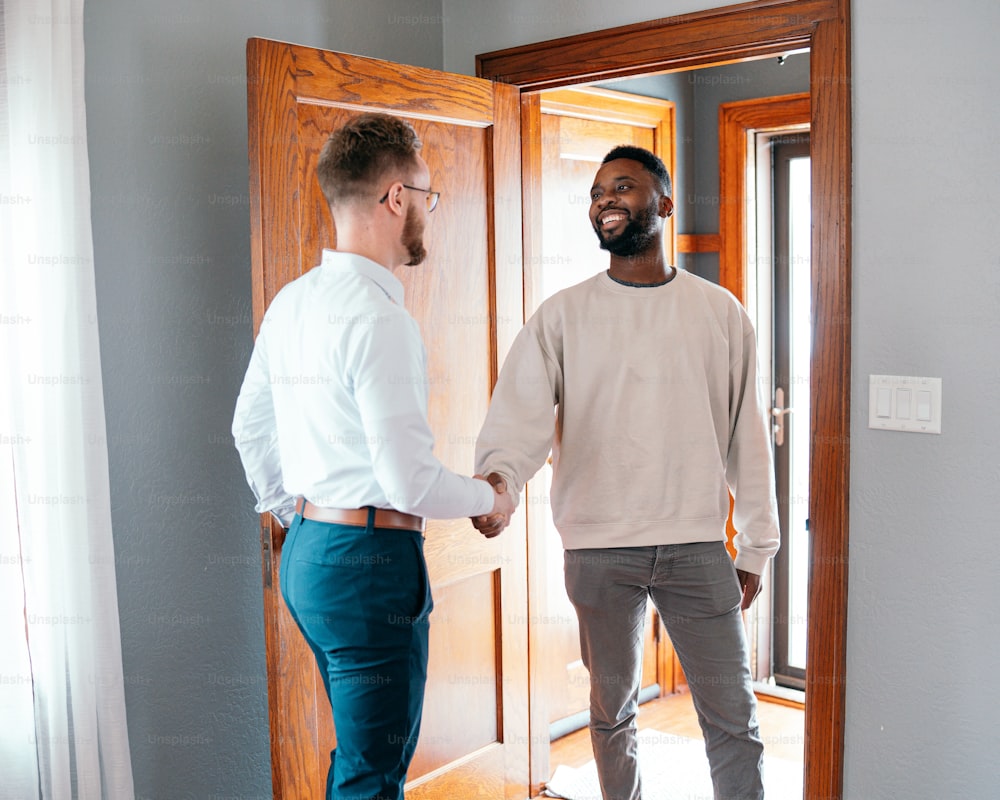 Dos hombres dándose la mano frente a una puerta